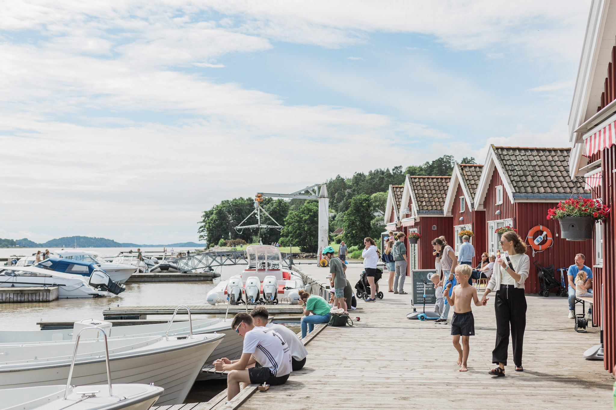 Oslofjord Marina på Brunstad — båter ved flytebryggene og rødmalte sjøbuer en sommerdag
