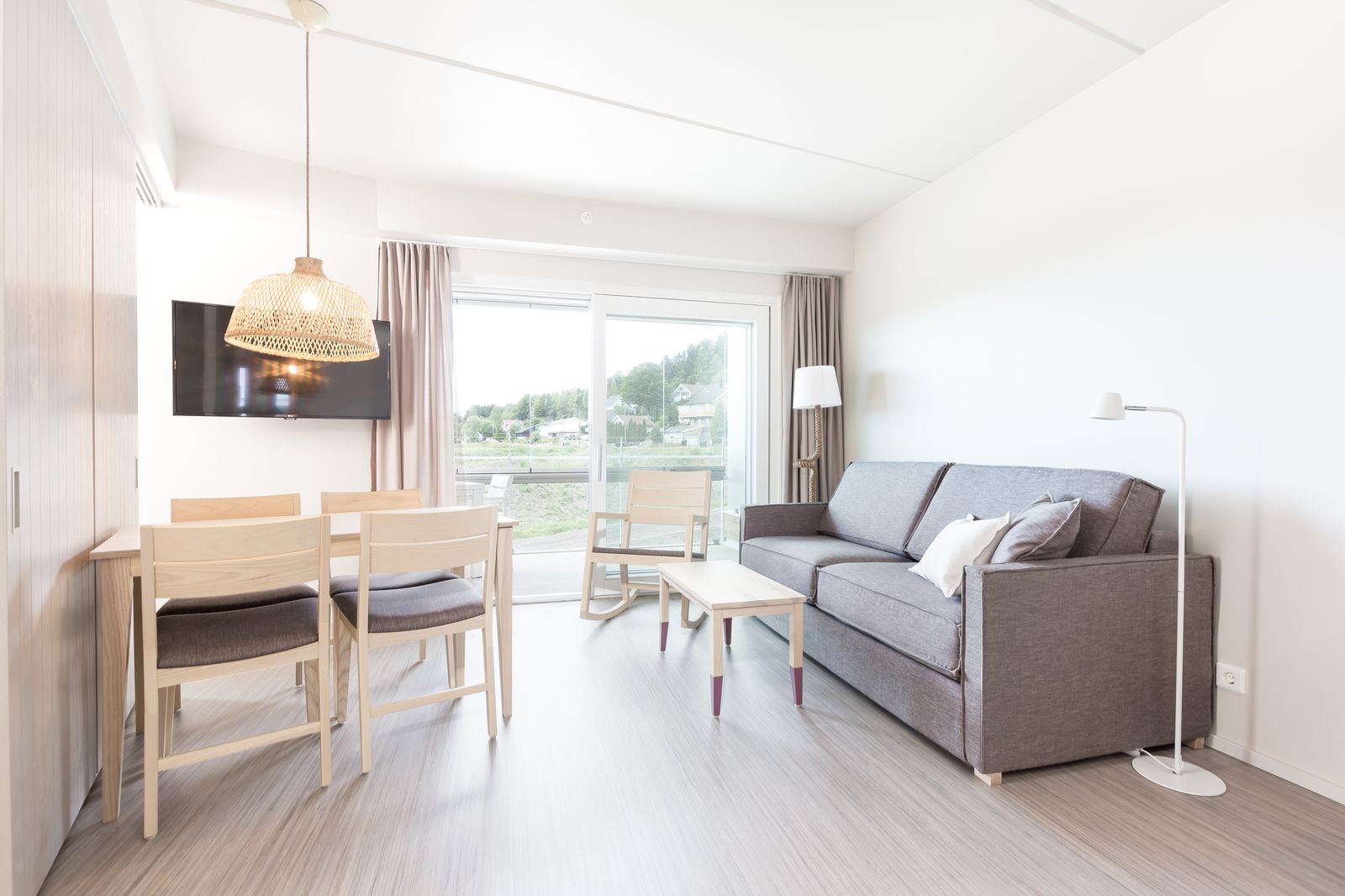 Interiør fra en suite på Brunstad — lys stue med sofa, spisebord og utsikt